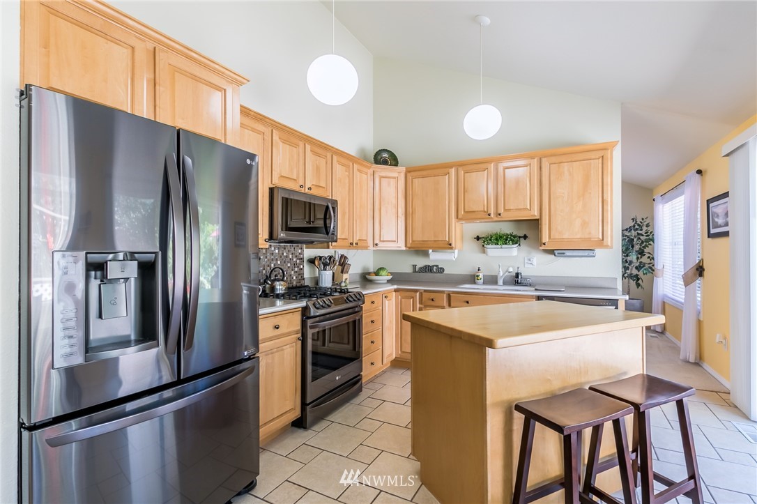 15612 Southeast 178th Street Renton, WA 98058 - Photo 21 of 40 a kitchen with stainless steel appliances granite countertop a refrigerator a stove a sink and a microwave