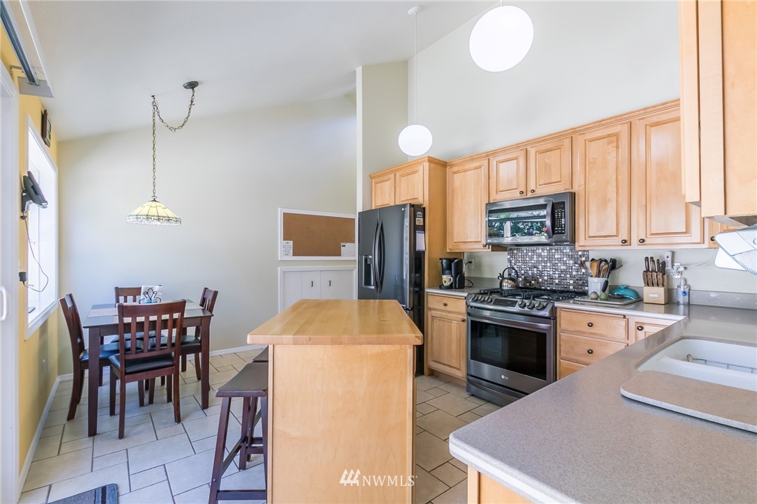 15612 Southeast 178th Street Renton, WA 98058 - Photo 22 of 40 a kitchen with stainless steel appliances a stove a sink a dining table and chairs