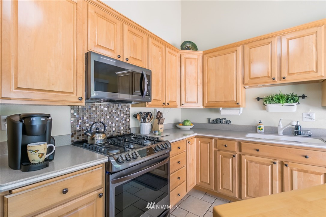 15612 Southeast 178th Street Renton, WA 98058 - Photo 24 of 40 a kitchen with stainless steel appliances granite countertop white cabinets a stove a sink and dishwasher