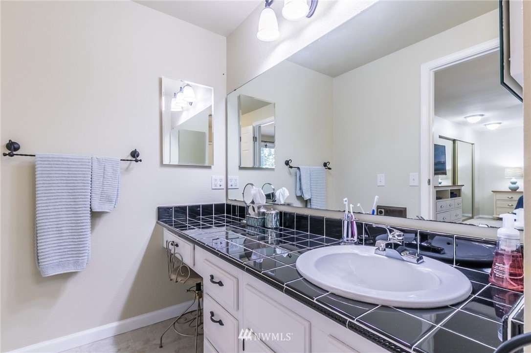 15612 Southeast 178th Street Renton, WA 98058 - Photo 32 of 40 a bathroom with a granite countertop sink a mirror and shower