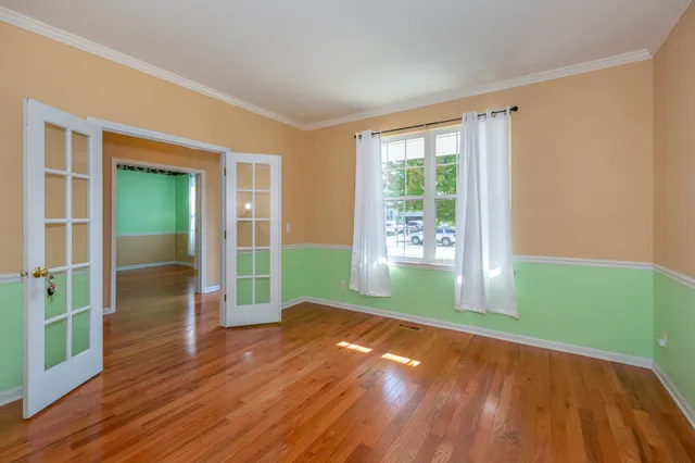 a view of empty room with wooden floor and fan