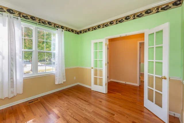 a view of an empty room with wooden floor and a window