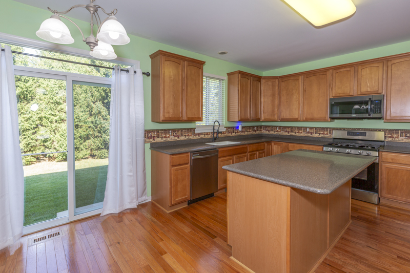 220 Stearn Drive Genoa, IL 60135 - Photo 9 of 42 a kitchen with kitchen island granite countertop a stove a sink and a microwave