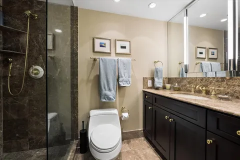 a bathroom with a granite countertop sink toilet and shower