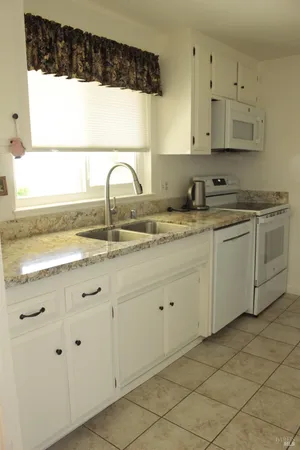 a kitchen with granite countertop white cabinets and a sink