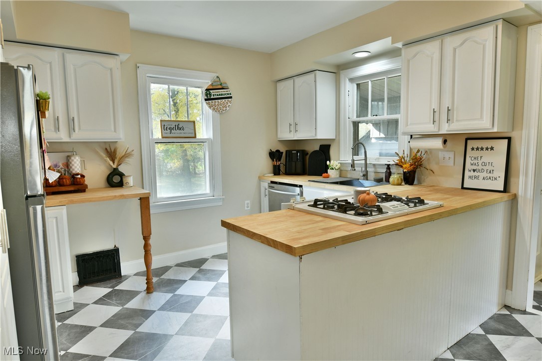572 Howland Wilson Road Southeast Warren, OH 44484 - Photo 10 of 50 Kitchen featuring appliances with stainless steel finishes, sink, butcher block countertops, kitchen peninsula, and white cabinets