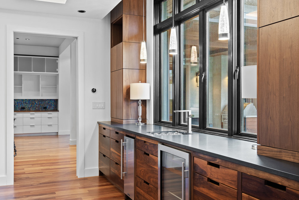 1905 Paisano Road Austin, TX 78746 - Photo 12 of 40 Rich hardwood floors complement bespoke cabinetry and a streamlined wet bar, creating an ideal entertainment space.