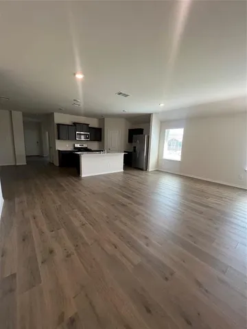 an empty room with kitchen view and a fireplace