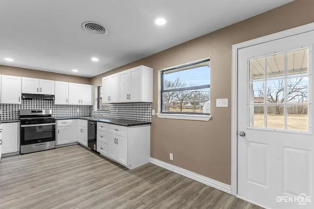 a kitchen with granite countertop a stove cabinets and wooden floor