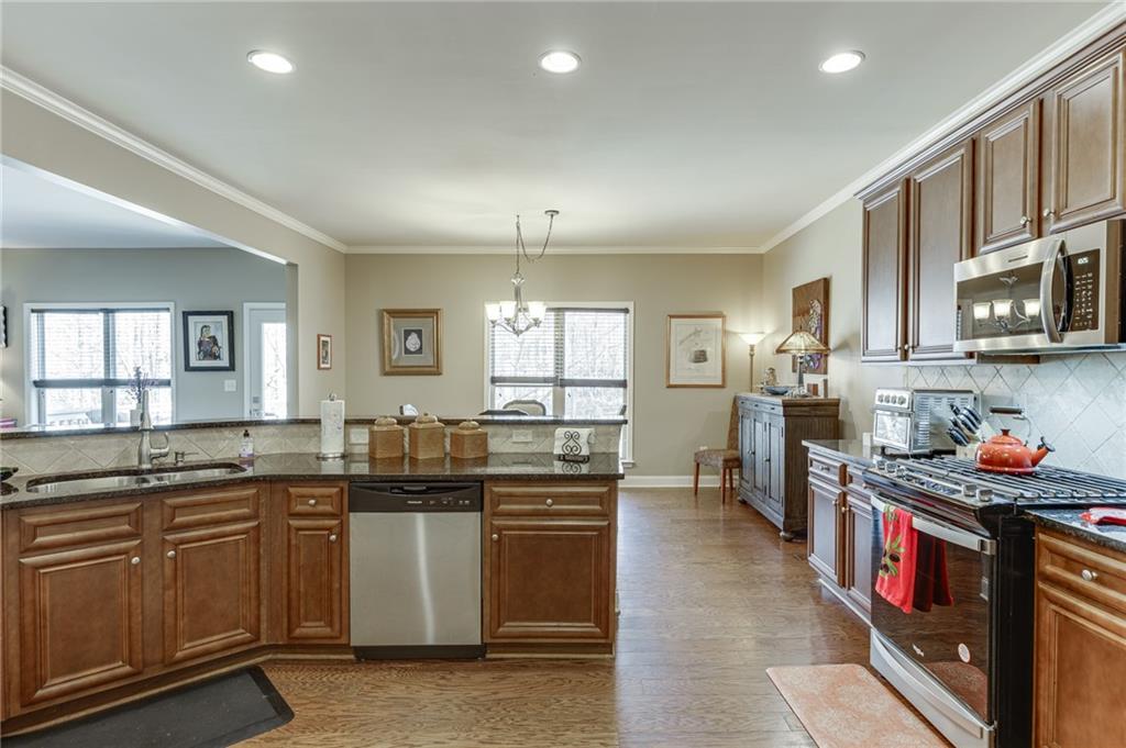2201 Spring Sound Lane Buford, GA 30519 - Photo 21 of 66 a kitchen with stainless steel appliances granite countertop a stove top oven a sink dishwasher and a refrigerator with wooden cabinets
