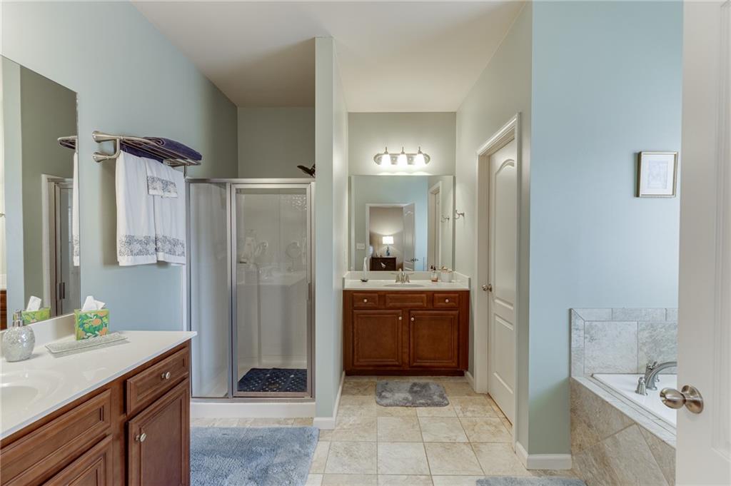 2201 Spring Sound Lane Buford, GA 30519 - Photo 40 of 66 a spacious bathroom with a granite countertop sink a toilet a mirror and shower