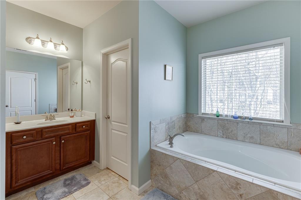 2201 Spring Sound Lane Buford, GA 30519 - Photo 42 of 66 a bathroom with a tub a sink and a large mirror