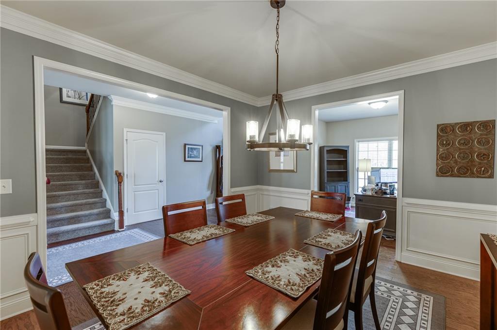 2201 Spring Sound Lane Buford, GA 30519 - Photo 7 of 66 a dining room with wooden floor a chandelier a wooden table and chairs