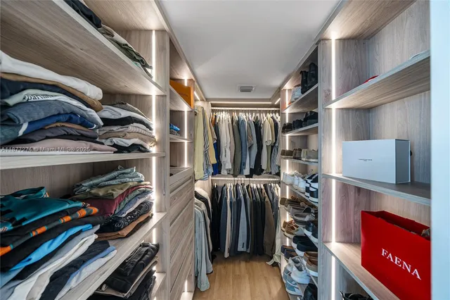 a view of walk in closet with clothes and shoes