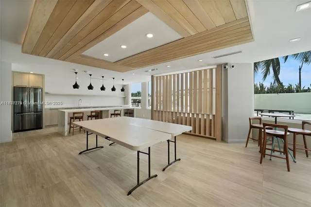 a kitchen with stainless steel appliances granite countertop a dining table chairs and refrigerator