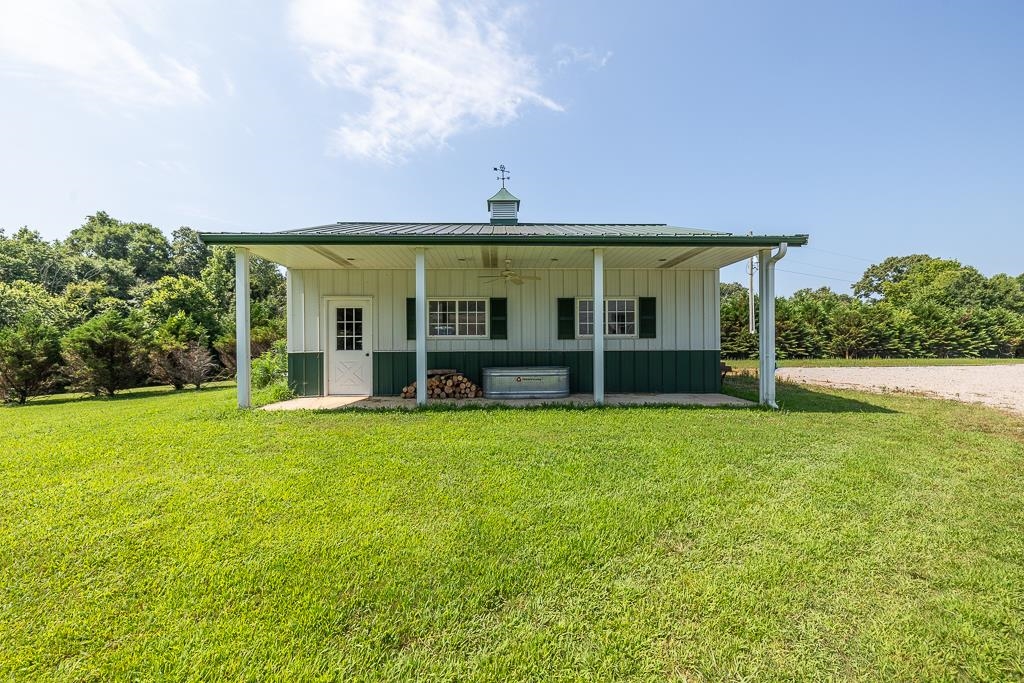 1915 Teague Store Road Somerville, TN 38068 - Photo 36 of 38 Two-tone white and green outbuilding featuring a covered porch, metal roof, cupola with weather vane, and a concrete patio