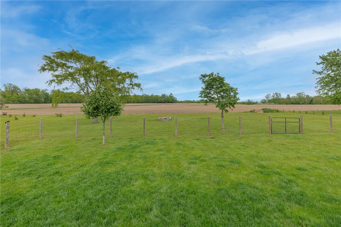 2645 Vance Road St. Paris, OH 43072 - Photo 29 of 35 A verdant, open field extends to distant trees under an azure sky, hinting at peaceful rural living.