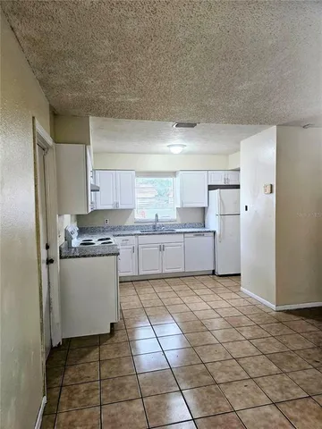 a kitchen with a refrigerator a stove top oven and white cabinets