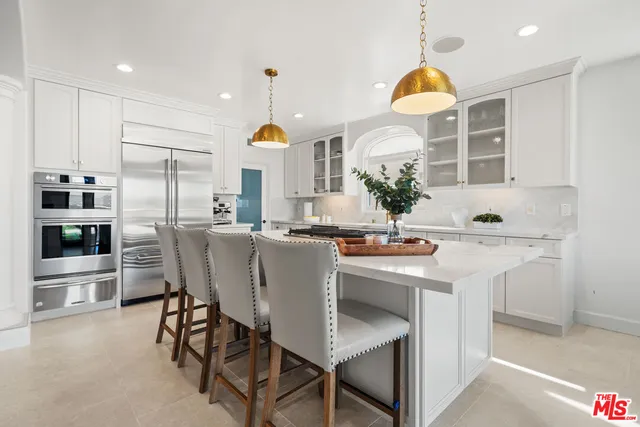 a kitchen with stainless steel appliances a dining table chairs and sink