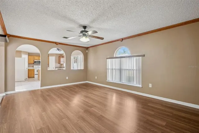 a view of an empty room with a window and wooden floor