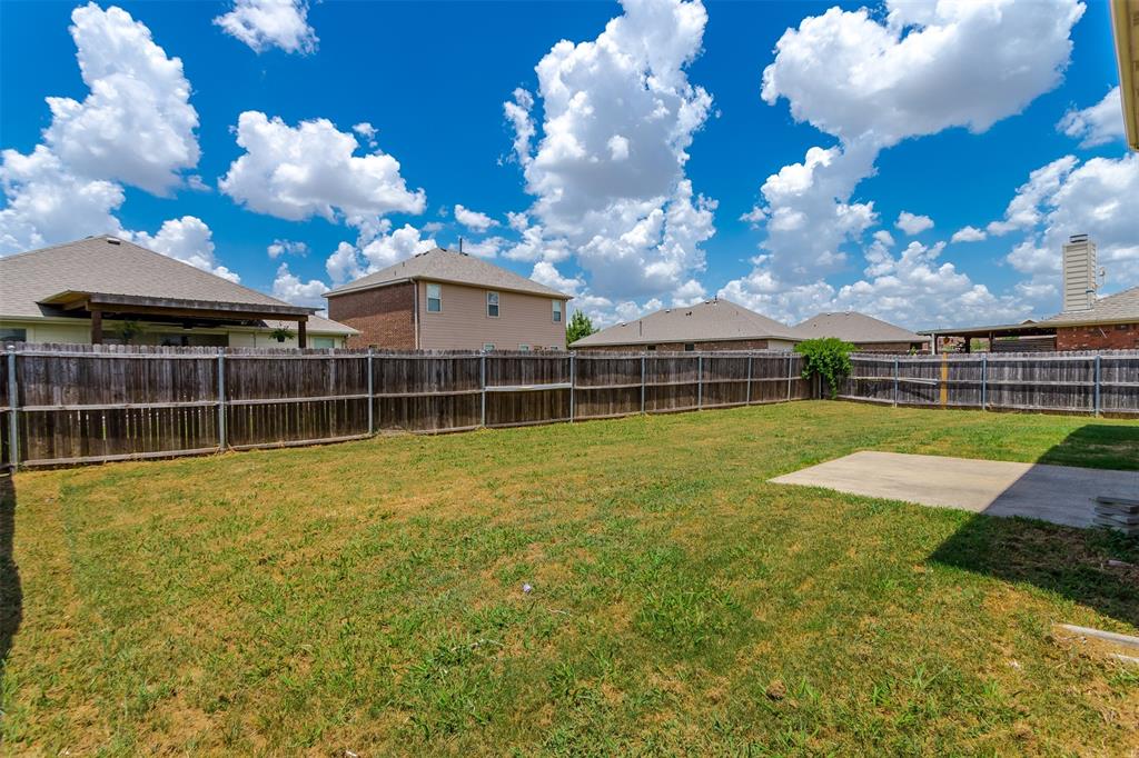 203 Arabian Road Waxahachie, TX 75165 - Photo 22 of 24 Expansive backyard featuring a wood privacy fence, a concrete patio area, and a lush green lawn