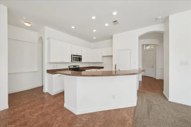 a large kitchen with stainless steel appliances a large counter top a stove and a refrigerator