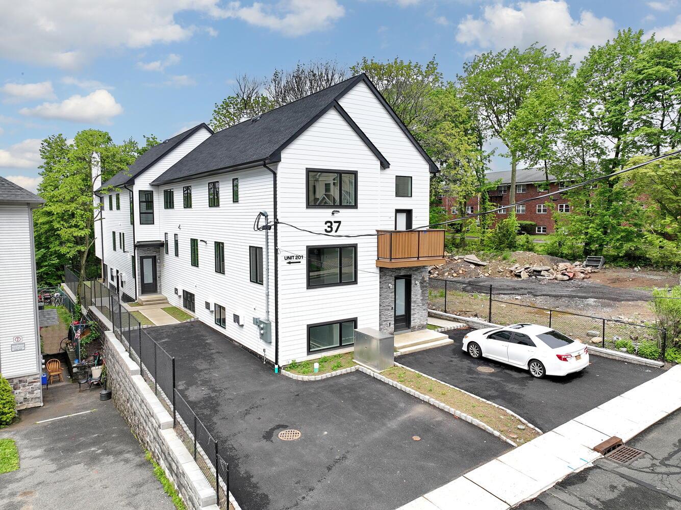 37 Ewing Avenue, Unit 202 Spring Valley, NY 10977 - Photo 2 of 44 a view of a white house with a small yard and large trees