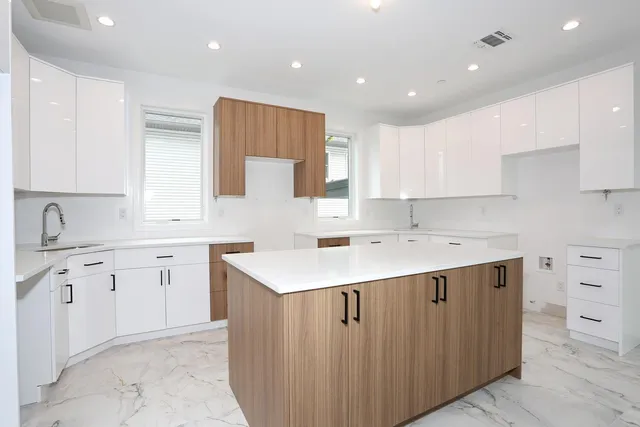a kitchen with a sink a stove a refrigerator and white cabinets