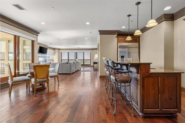 a open kitchen with stainless steel appliances granite countertop a stove top oven a dining table and chairs with wooden floor