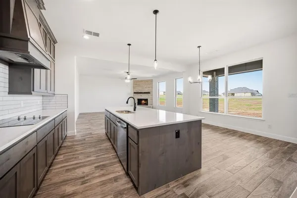 a kitchen with stainless steel appliances granite countertop a sink a stove and a wooden floors