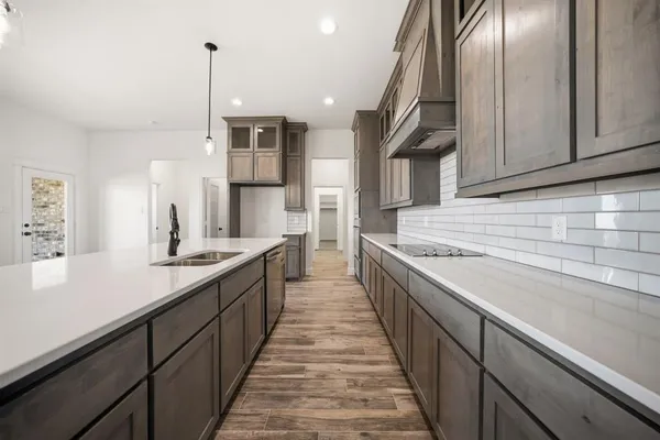 a large kitchen with stainless steel appliances granite countertop a sink and dishwasher a stove top oven with wooden floor