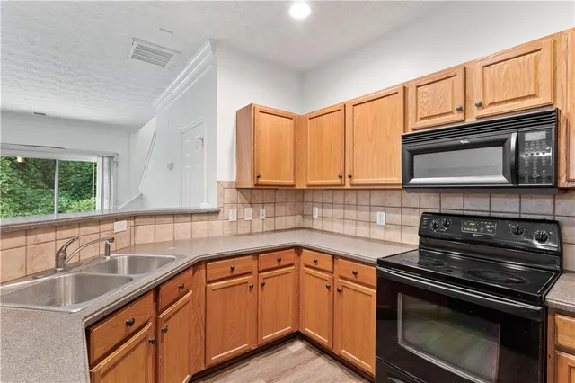 a kitchen with granite countertop a sink stainless steel appliances and cabinets