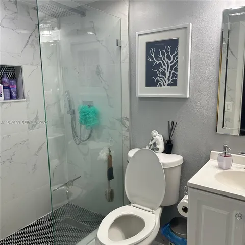 a white toilet sitting next to a bathroom sink and a shower