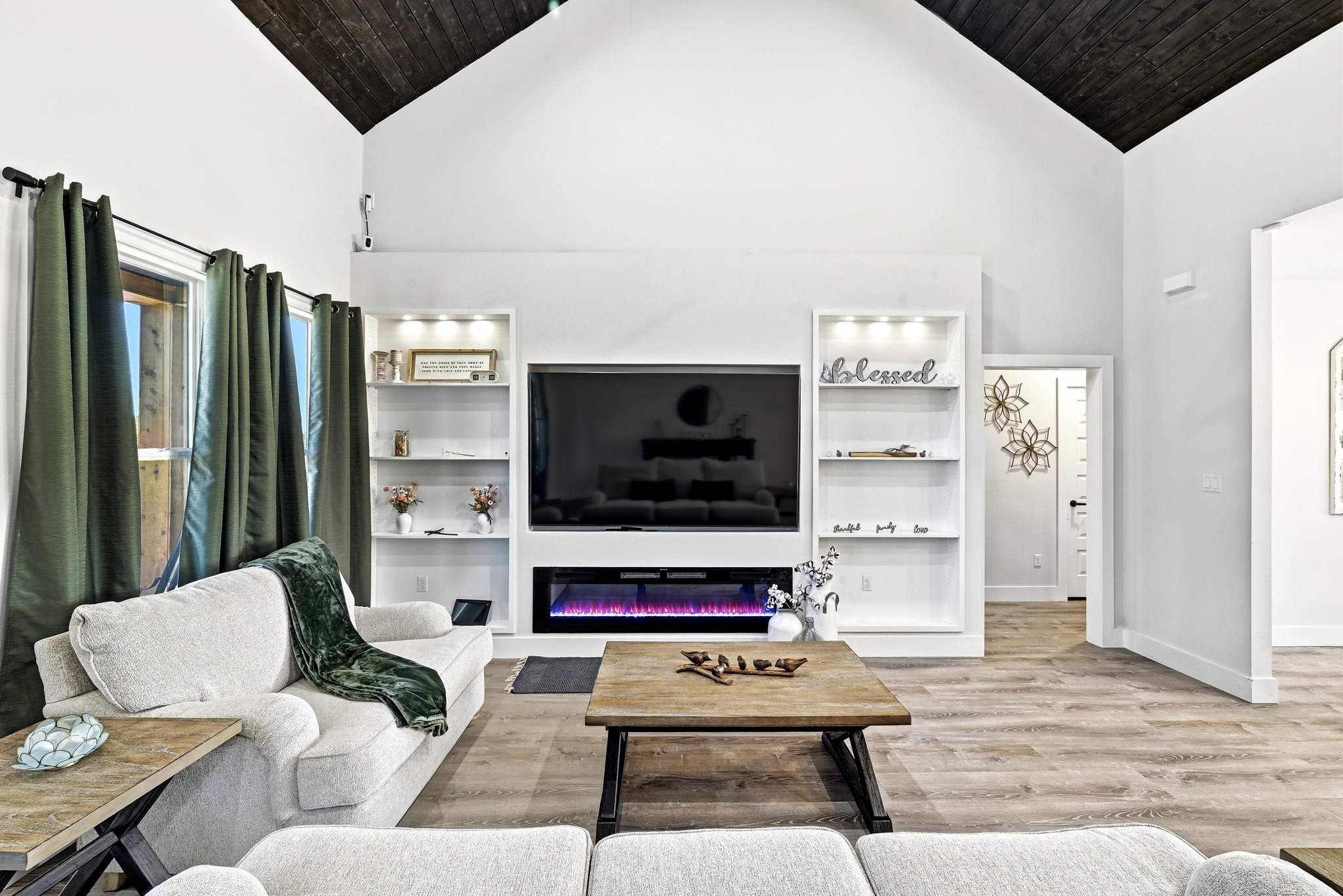 2889 Old McMahan Road Lockhart, TX 78644 - Photo 8 of 33 A striking vaulted ceiling with dark wood beams crowns a modern living space featuring a linear electric fireplace.