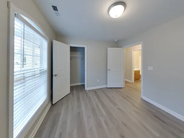 an empty room with wooden floor and windows