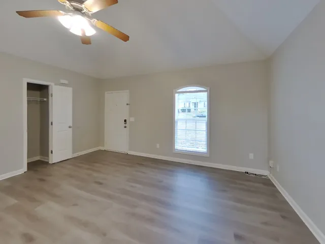 a view of an empty room with wooden floor and a window