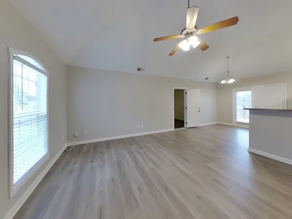 a view of an empty room with window and wooden floor