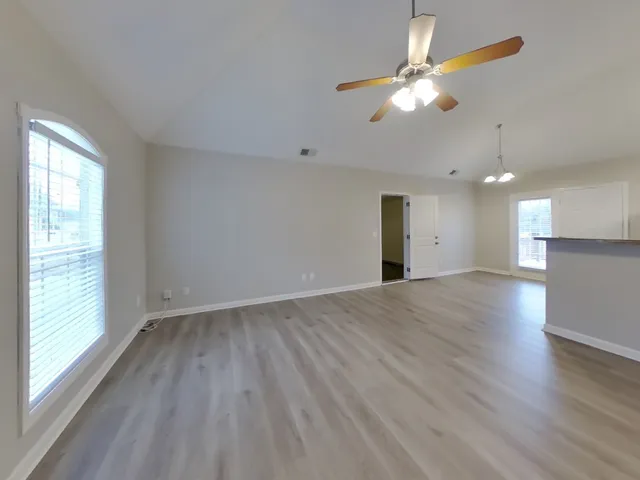 a view of an empty room with window and wooden floor