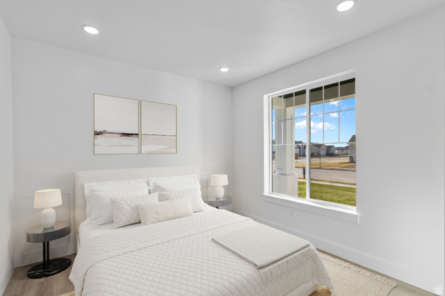 257 West 2950th Street South Logan, UT 84321 - Photo 3 of 11 Bright secondary bedroom featuring a white quilted bedside table, recessed ceiling lighting, and large picture window with expansive outdoor scenery