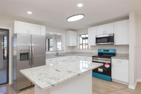 a kitchen with stainless steel appliances granite countertop a refrigerator a stove and a sink