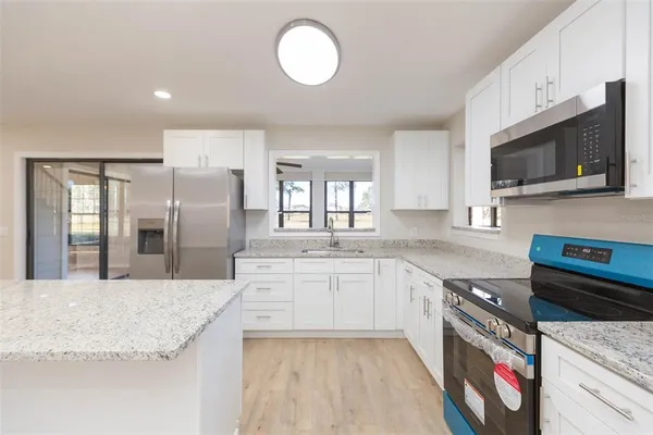 a large kitchen with stainless steel appliances granite countertop a stove a sink and a microwave