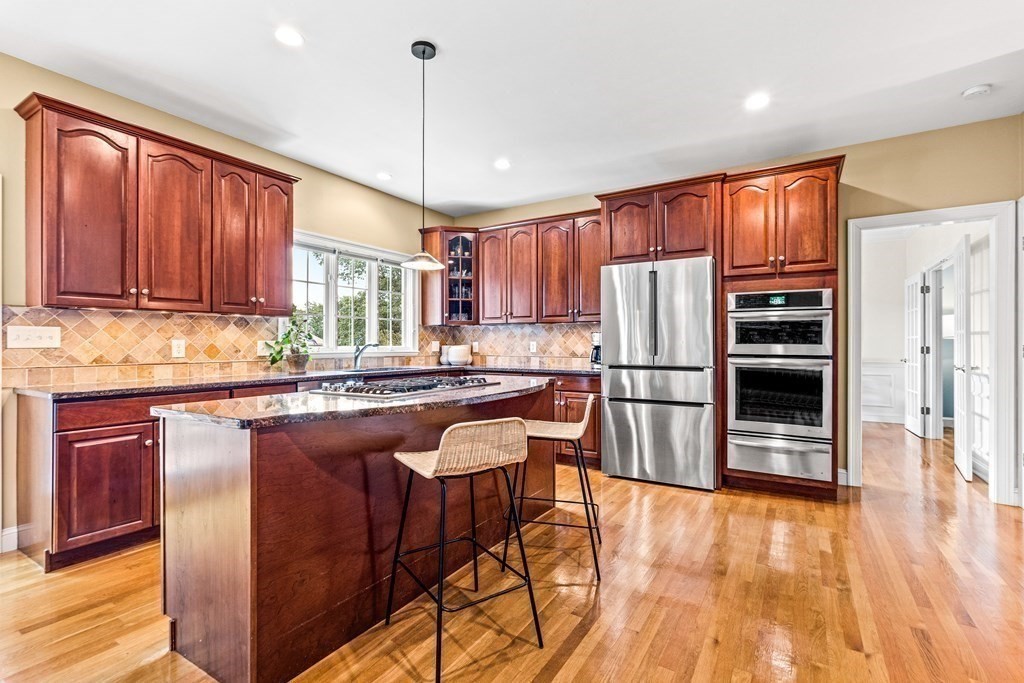 17 Crown Ridge Road Wellesley, MA 02482 - Photo 7 of 37 a kitchen with stainless steel appliances granite countertop a refrigerator a sink dishwasher a stove and a dining table with wooden floor