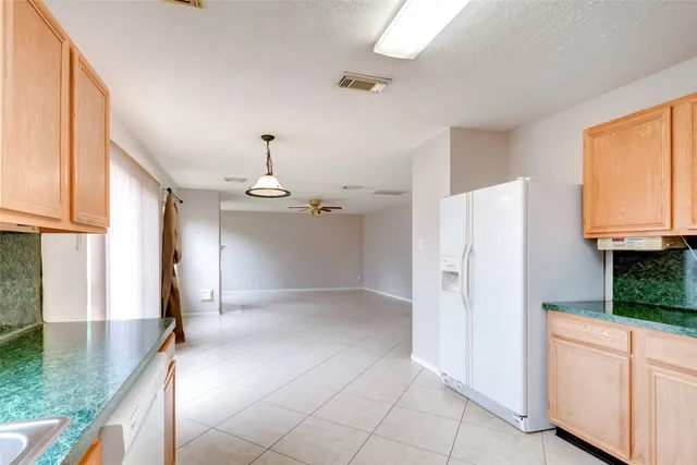 a view of a kitchen with a sink and dishwasher a refrigerator with white cabinets