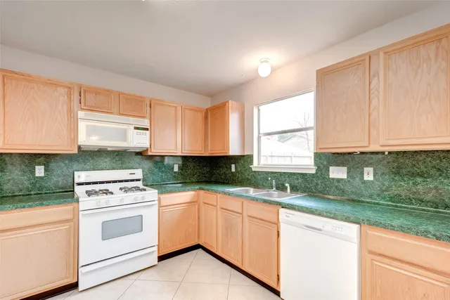 a kitchen with granite countertop white cabinets and white appliances