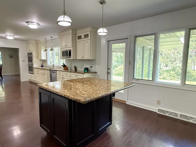 a kitchen with center island wooden floor center island and stainless steel appliances