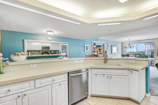 a kitchen with stainless steel appliances kitchen island granite countertop a dining table chairs and a refrigerator