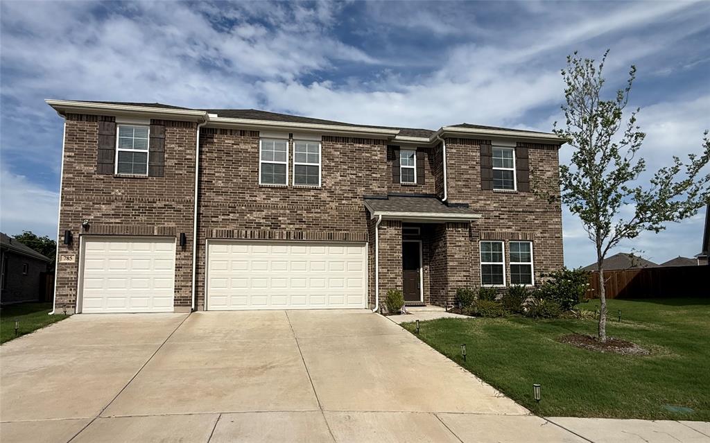 Two-story brick exterior featuring a two-car garage, an additional single-car garage, brown paneled shutters, a covered entry, and a manicured front lawn