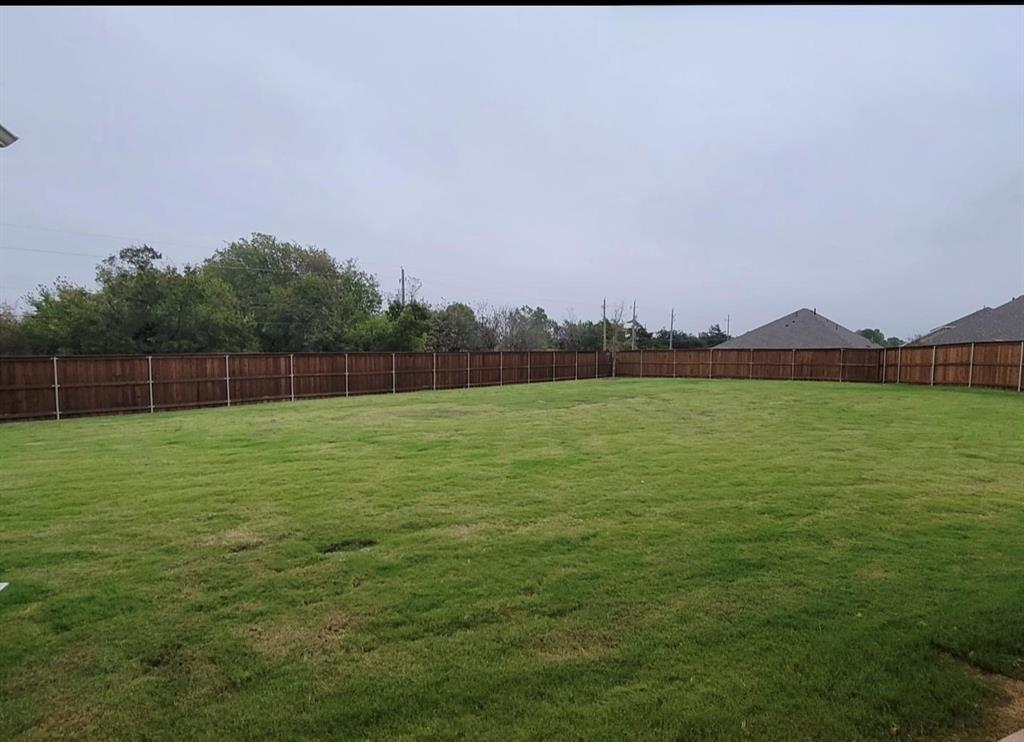 785 Vineyard Way Forney, TX 75126 - Photo 12 of 12 The property features an expansive lawn with a wooden fence enclosing the perimeter