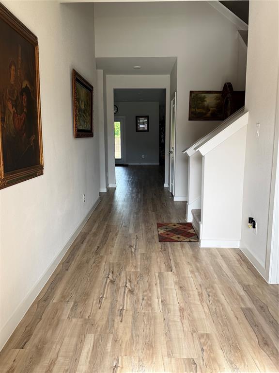 785 Vineyard Way Forney, TX 75126 - Photo 2 of 12 Spacious hallway featuring wood-finish flooring, white baseboards, and a built-in staircase with a wood handrail