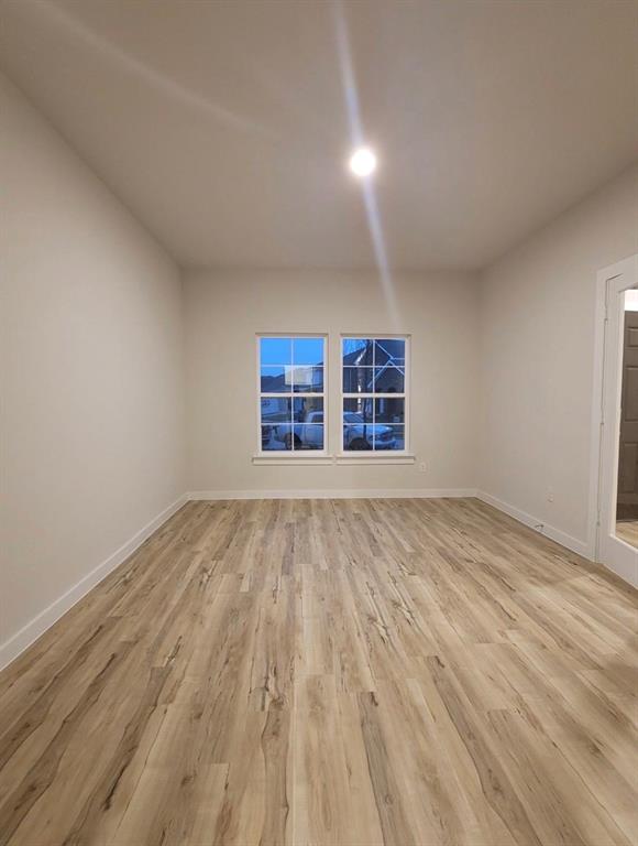 785 Vineyard Way Forney, TX 75126 - Photo 3 of 12 Spacious room featuring wood-finish flooring, neutral-toned walls, and white baseboards